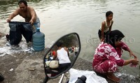Dua orang warga mencuci pakaian di sungai.