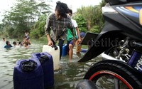 Warga mengambil air sungai menggunakan jeriken.