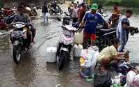 Sejumlah warga mengangkut air sungai menggunakan motor.