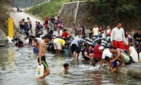 Warga ramai-ramai mencuci pakaian di sungai.