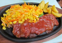 Steak sirloin berwarna kecokelatan ini berukuran cukup besar dengan pelengkap sayuran dan kentang goreng. Siraman saus BBQ yang gurih manis di atas daging empuk menambah kelezatan sajian ini.
