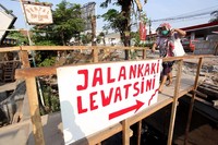 Seorang warga melintas di jembatan darurat.