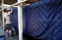 Seorang pekerja di usaha batik Farras Batik menyelesaian proses penjemuran kain batik cap motif Geblek Renteng yang digunakan siswa SD dan SMP se-Kabupaten Kulonprogo.
