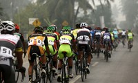 Iring-iringan pebalap melintasi jalanan yang diselimuti kabut asap.