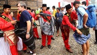 Uda Duta Wisata Tanah Datar memakaikan sarung ke pebalap.