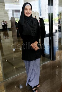 Dewi tampil dibalut hijab, busana dan heels hitam dipadu dengan rok abu-abu. Pool/Palevi S/detikFoto.