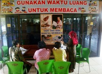 Sejumlah penumpang membaca buku sambil menunggu kedatangan bus yang akan ditumpangi.