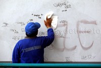Petugas membersihkan coretan yang menghiasi dinding.