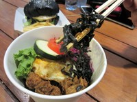 Black Magic Noodle hadirkan mie keriting yang pipih lebar dengan pelengkap selada, mentimun Jepang, tomat, kubis ungu, potongan daging ayam, dan telur mata sapi.