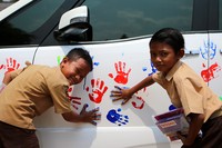 Para siswa SD di Lampung membubuhkan cap tangan di badan mobil Nissan Serena. Ist/Nissan.