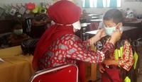Anak-anak yang belajar di kelas harus memakai masker.