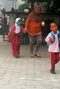 Seorang ibu mengantar anaknya ke sekolah.