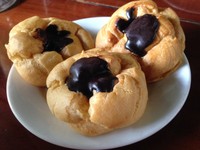Moorkoppen yang mirip sus dengan sedikit pemakaian cokelat beku di permukaannya. Aroma rum begitu pekat pada vla yang manis lembut.