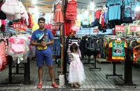 Pedagang menunggu calon pembeli di depan kiosnya.