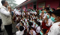 Anis memberikan contoh memakai masker yang benar kepada para siswa.