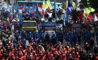 Buruh membawa atribut aksi seperti spanduk, poster, dan bendera.
