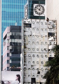 Seorang pekerja melakukan perawatan papan reklame.