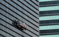 Sejumlah pekerja bergelantungan membersihkan kaca gedung. Pekerjaan itu cukup berbahaya karena dilakukan di ketinggian.