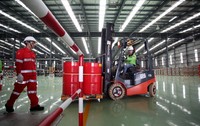 Pekerja memindahkan drum berisi pelumas di bagian Filling Hall.
