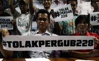 Mereka membentangkan spanduk bertuliskan tolak Pergub 228