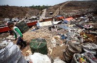 Seorang pemulung melintas di samping antrean truk.
