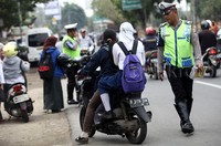 Polisi meminta pengendara yang tidak memakai helm untuk berhenti.