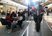 Pengunjung mal Pondok Indah Mall 2 menyimak penjelasan tenaga penjual soal motor Aprilia.
