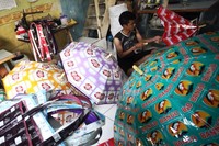 Perajin mencoba payung buatannya.