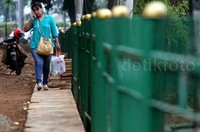 Seorang warga melintas di sisi pagar besi yang telah dipasang oleh petugas di JCC Senayan.