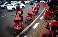Puluhan wanita berkaos merah menggelar aksi damai dengan membawa dorongan bayi di kawasan bundaran Patung Indosat Jakarta, Jumat (13/11/2015).