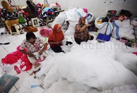 Pekerja menyiapkan bahan-bahan pembuatan boneka.