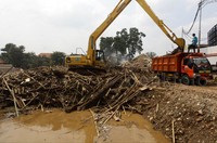 Sejak pagi sampah di sungai yang didominasi kayu dan bambu diangkut ke luar sungai. Alat berat mengangkat sampah kayu dan bambu kedalam truk.