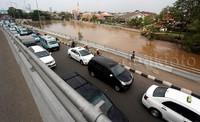 Debit air Sungai Ciliwung hampir menyentuh permukaan jalan.