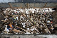 Petugas membersihkan sampah yang tersangkut di pintu air Manggarai.