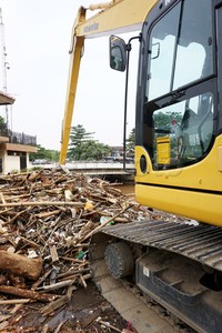 Ekskavator mengeruk sampah di pintu air Manggarai.