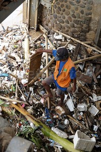 Petugas membersihkan sampah di pintu air Manggarai.