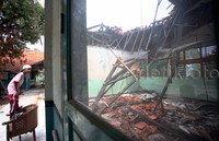 Seorang siswa melihat ruang kelasnya yang hancur.