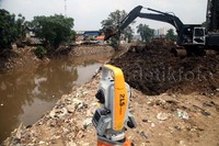 Alat berat mengeruk tanah untuk pelebaran Kali Ciliwung.