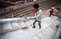 Pekerja membawa material banguna ke atas JPO.