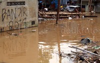 Warga membersihkan sampah yang terbawa banjir.