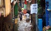 Warga melintasi gang yang terendam banjir.