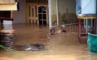 Beberapa anak asyik bermain air di depan rumahnya.