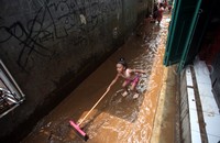 Dua orang anak ikut membantu membersihkan lumpur di depan rumahnya.