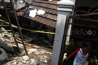 Seorang anak bermain di depan rumah yang hancur akibat ledakan tabung gas.