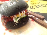 Makanan serba hitam masih menjadi tren. Black Burger dengan porsi jumbo ini bisa Anda nikmati dengan harga 25.000 rupiah saja.