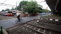 Pengendara sepeda nekat menerobos saat pintu perlintasan kereta tertutup.