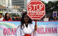 Seorang pegiat menunjukan poster yang bertuliskan  Stop Kekerasan Seksual.