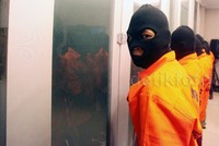Para tersangka tampak mengenakan baju tahanan dann penutup muka.