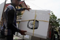 Seorang petugas menurunkan bilik suara dari atas mobil bak terbuka. Pool/Lamhot Aritonang/detikFoto.