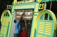Petugas memasang bacaan selamat datang di pintu TPS.